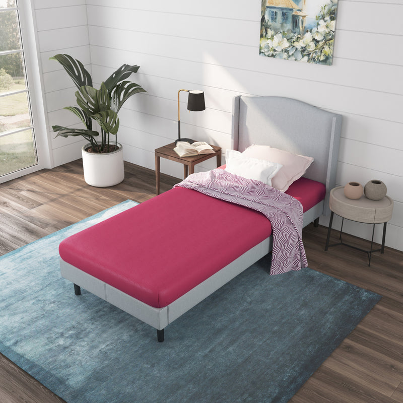a bed with pink kids mattress and pillows in a room with windows