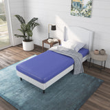 a bed with a blue kids mattress and a lamp on a rug in a room with windows