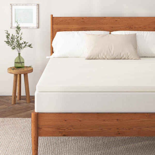 a bed with a white mattress topper and a wooden frame and a plant in a vase