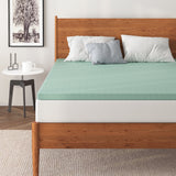 a bed with a green mattress topper